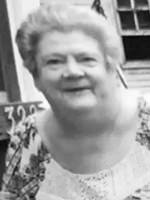 Portrait of an elderly woman with short gray hair, smiling, wearing a light patterned blouse.