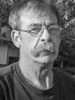 Middle-aged man with gray hair and a mustache wearing glasses outdoors.