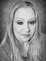 Head-and-shoulders black-and-white portrait of a woman with long hair looking at the camera, neutral expression.