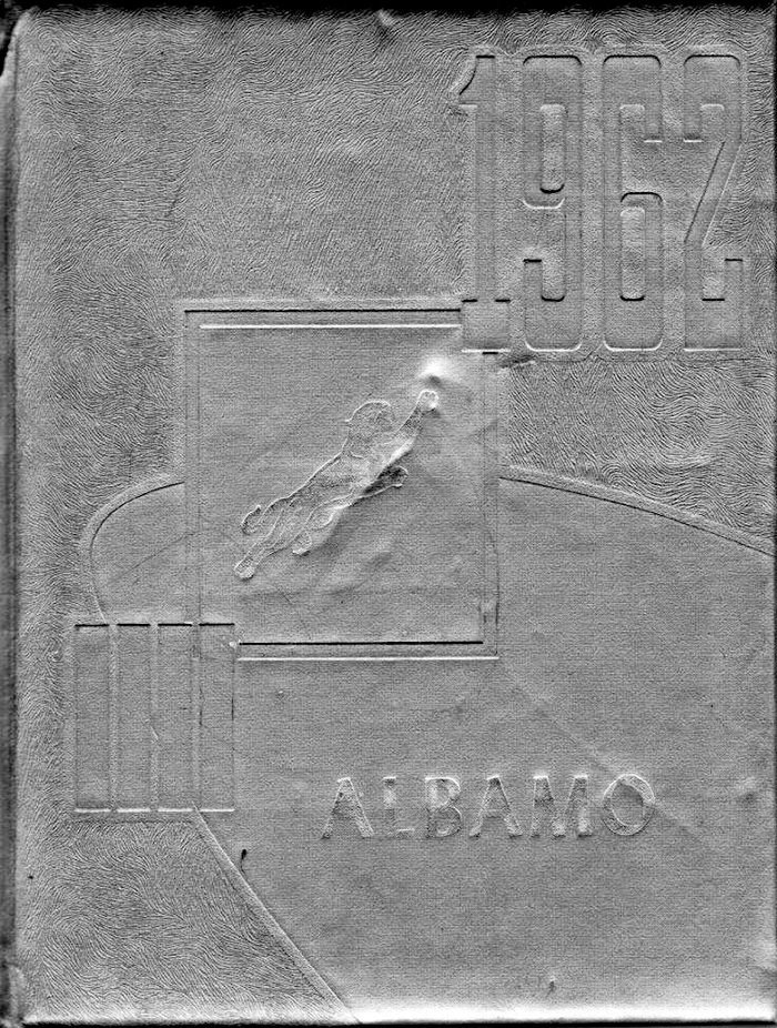 Close-up of a textured metal plaque with embossed numerals at the top right and Greek lettering near the bottom; a small rectangular inset shows a raised, abstract shape.