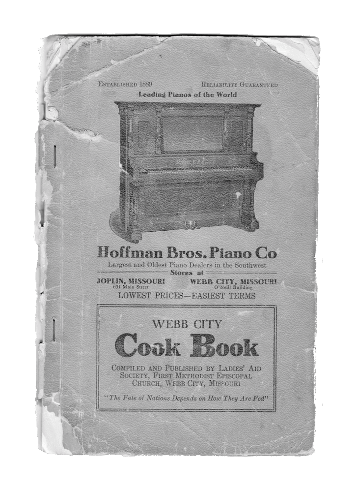 Vintage, worn cookbook cover titled 'Webb City Cook Book' with a piano company advertisement and weathered edges.