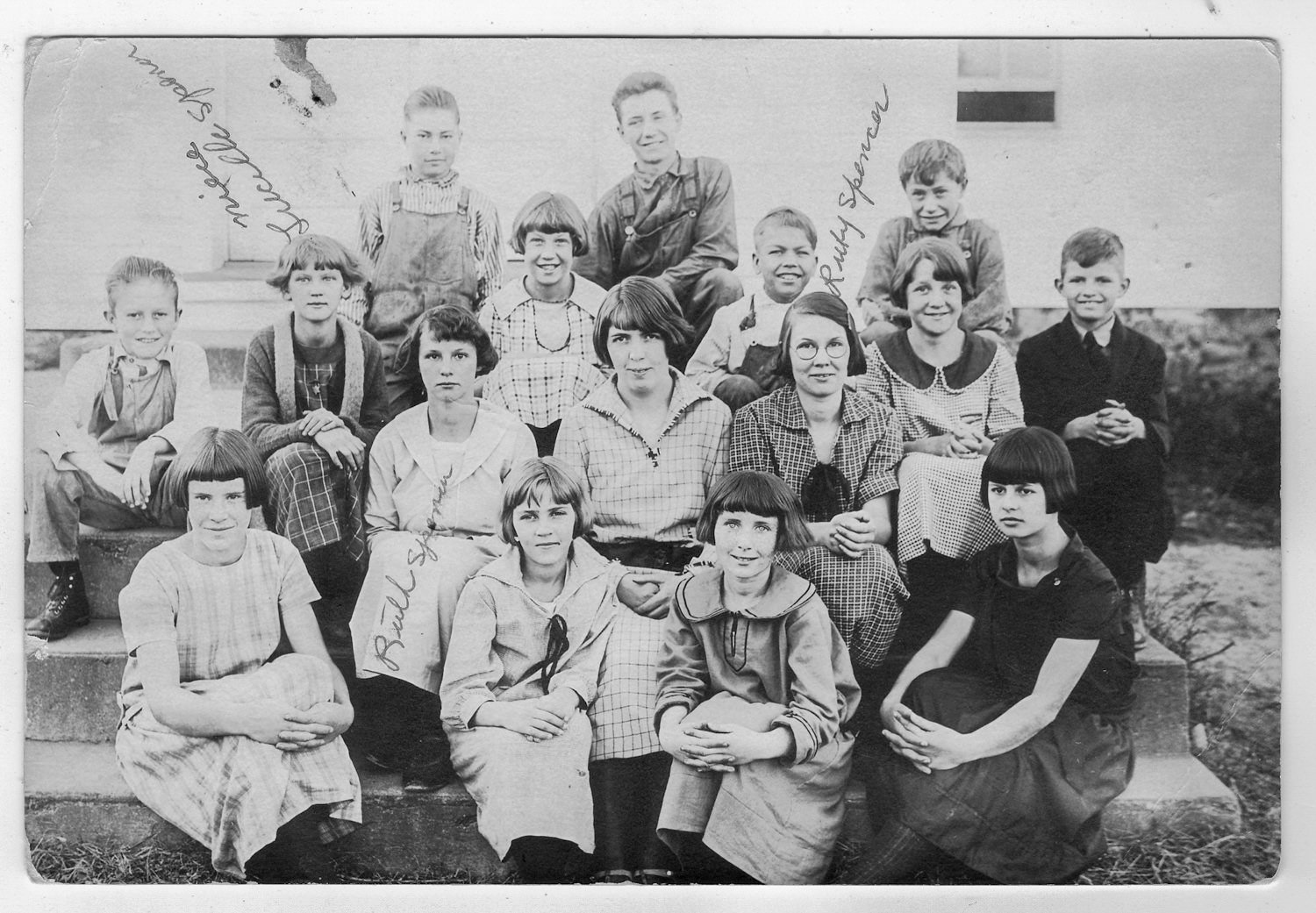 Group of schoolchildren posed on steps outside for a class photo, smiling at the camera.