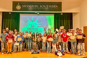 Group of students on a stage posing for a photo at Missouri Southern State University.