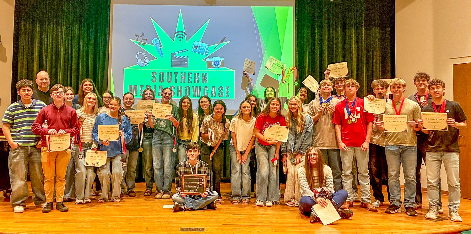 Group of students on a stage proudly holding certificates and medals at Southern Showcase.